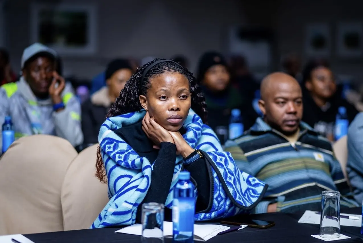 A participant wrapped in a blue Basotho blanket listens intently during a GEM community session.