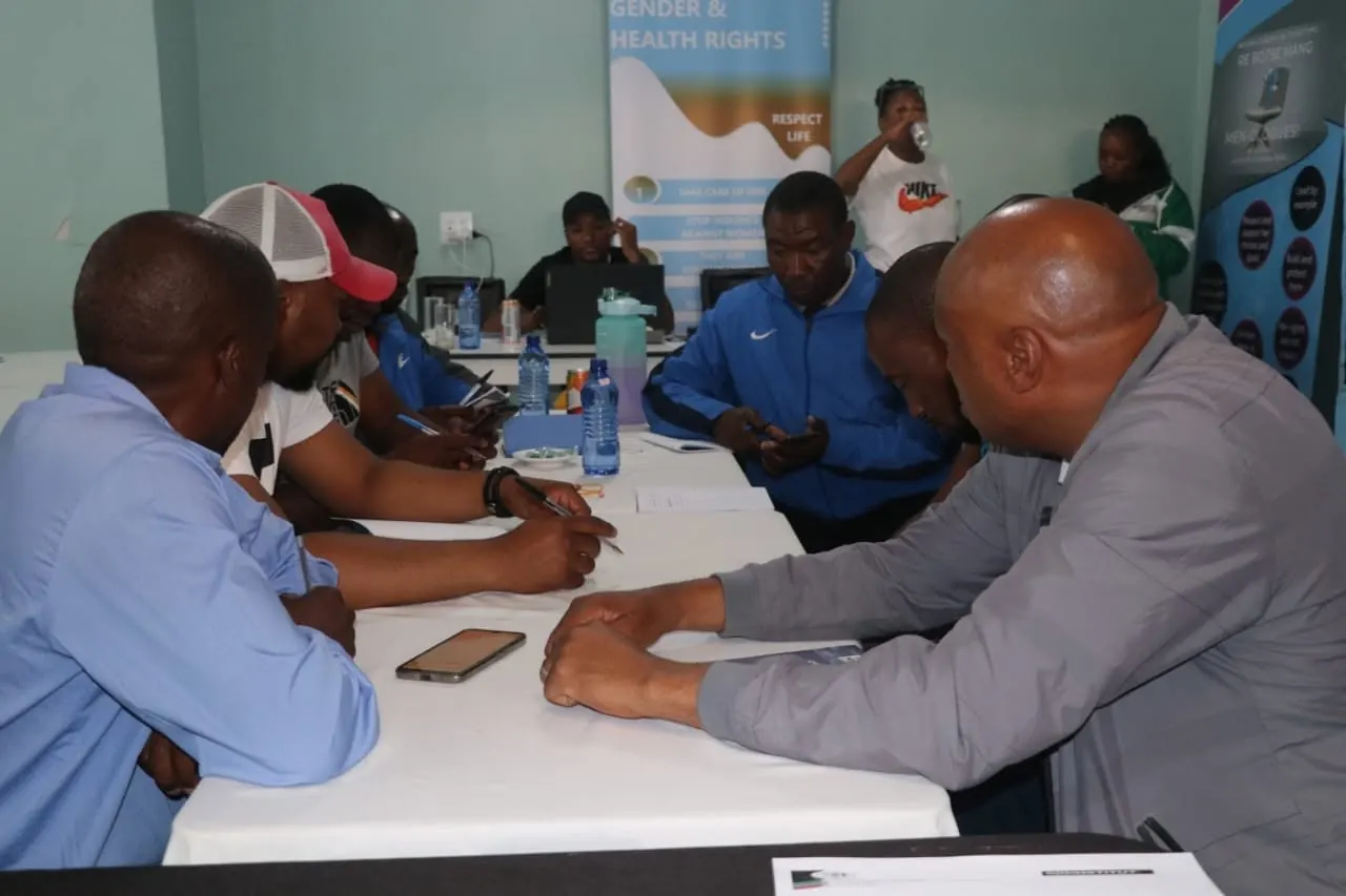 Men work through printed materials together during a Men-Logues gender and health rights dialogue.